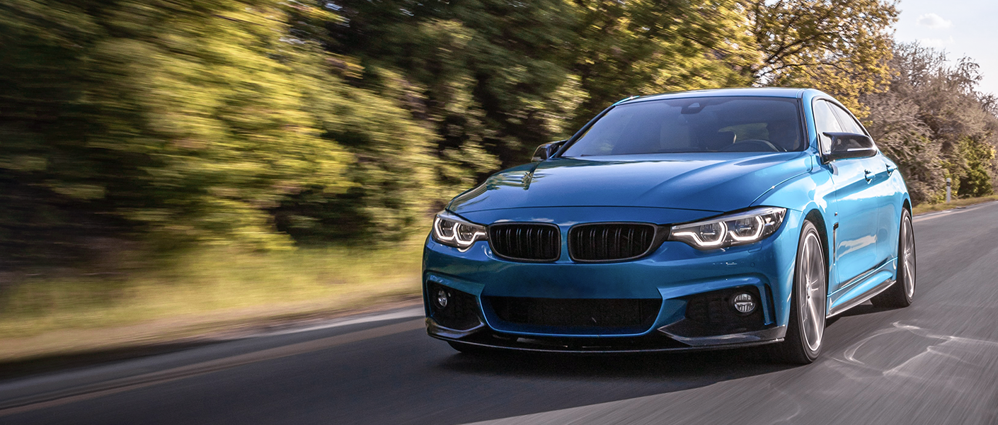 Blue BMW driving on a road.