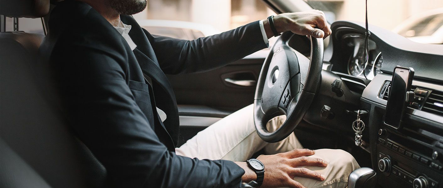 Man in suit driving a car.